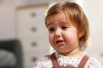 Photo of Cute little baby girl crying at home, space for text