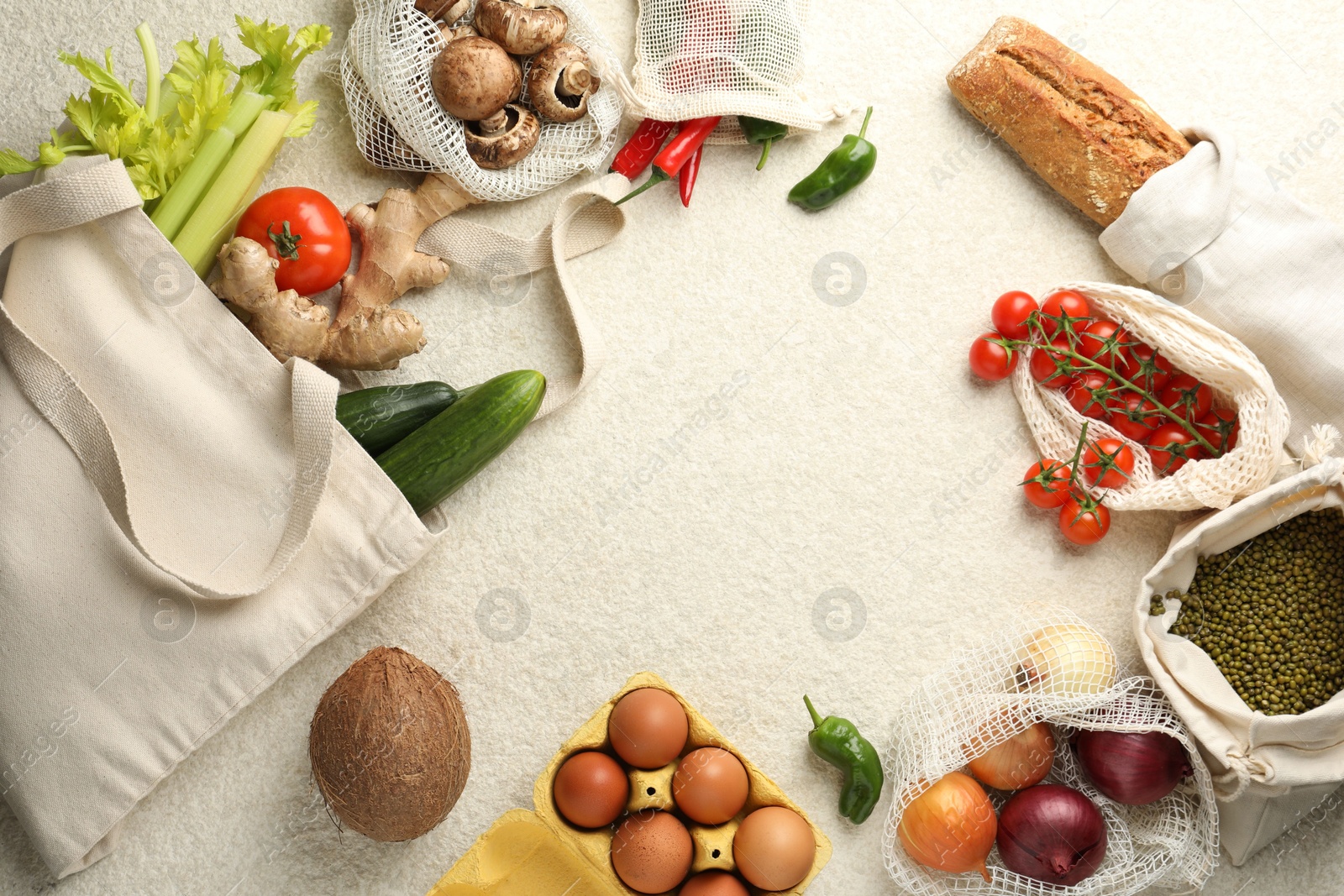 Photo of Eco bags with different food products on white textured table, flat lay. Space for text