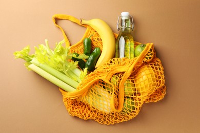 Photo of Eco bag with vegetables, fruits and bottle of drink on dark beige background, top view