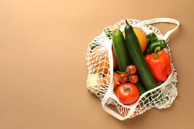 Photo of Eco bag with vegetables and fruits on dark beige background, top view. Space for text