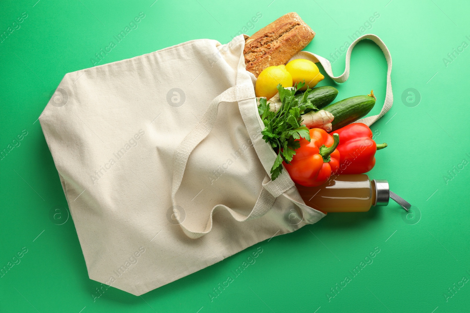 Photo of Eco bag with different food products and juice on green background, top view