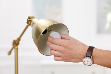 Photo of Man changing light bulb in lamp at home, closeup