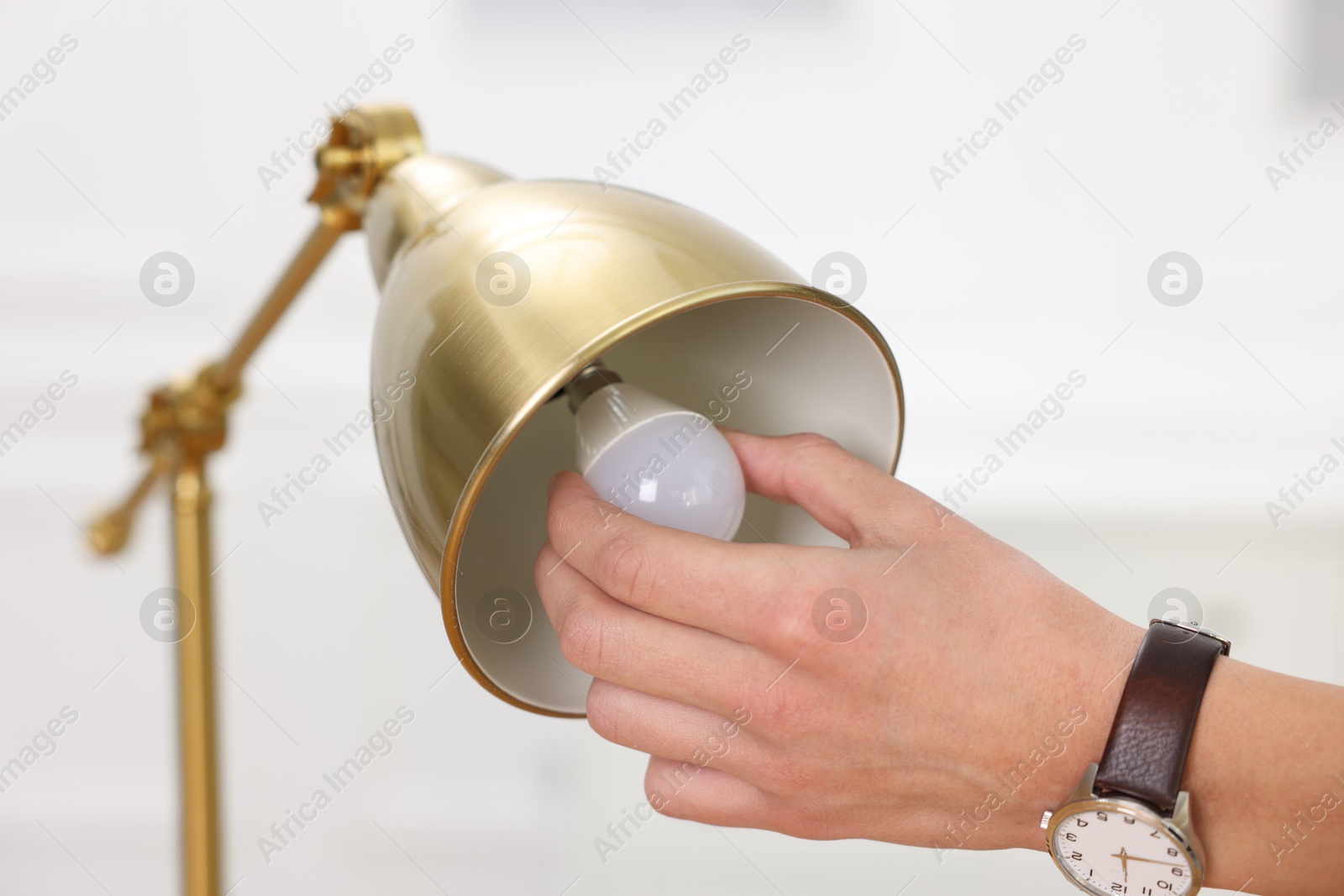 Photo of Man changing light bulb in lamp at home, closeup