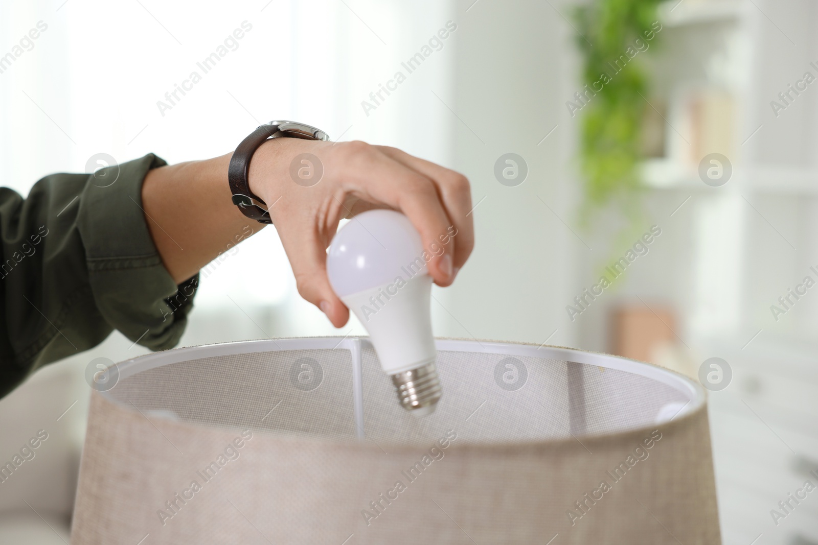 Photo of Man changing light bulb in lamp at home, closeup