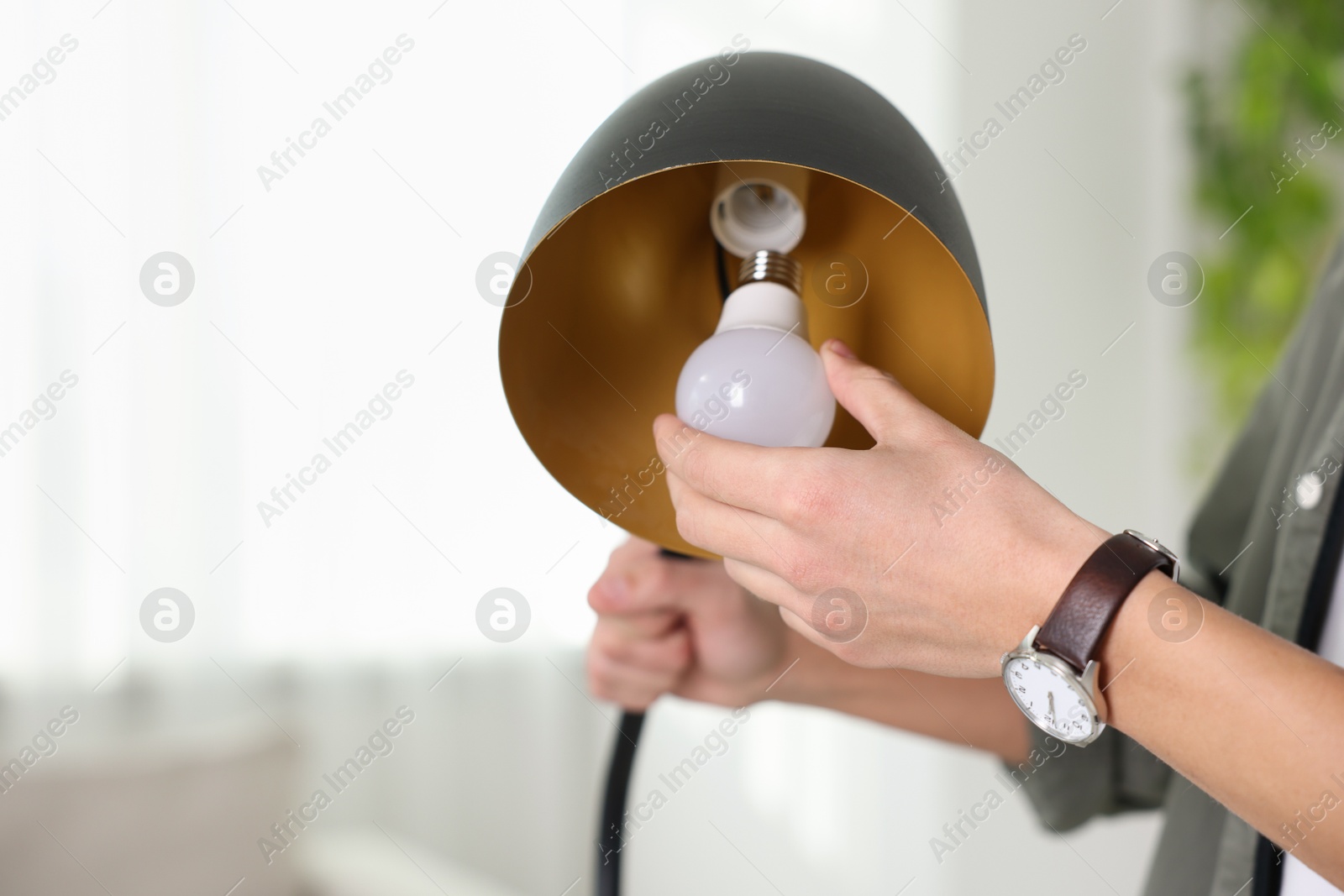 Photo of Man changing light bulb in lamp at home, closeup. Space for text