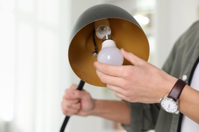 Photo of Man changing light bulb in lamp at home, closeup. Space for text