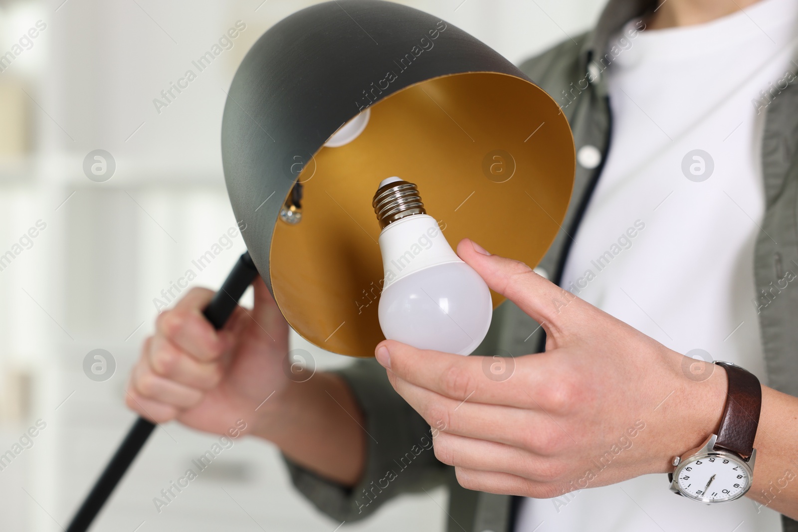 Photo of Man changing light bulb in lamp at home, closeup