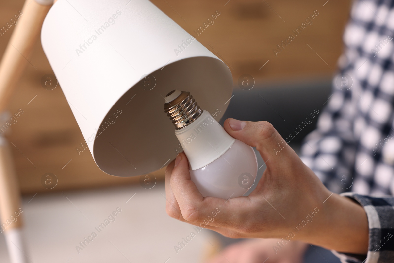 Photo of Man changing light bulb in lamp at home, closeup