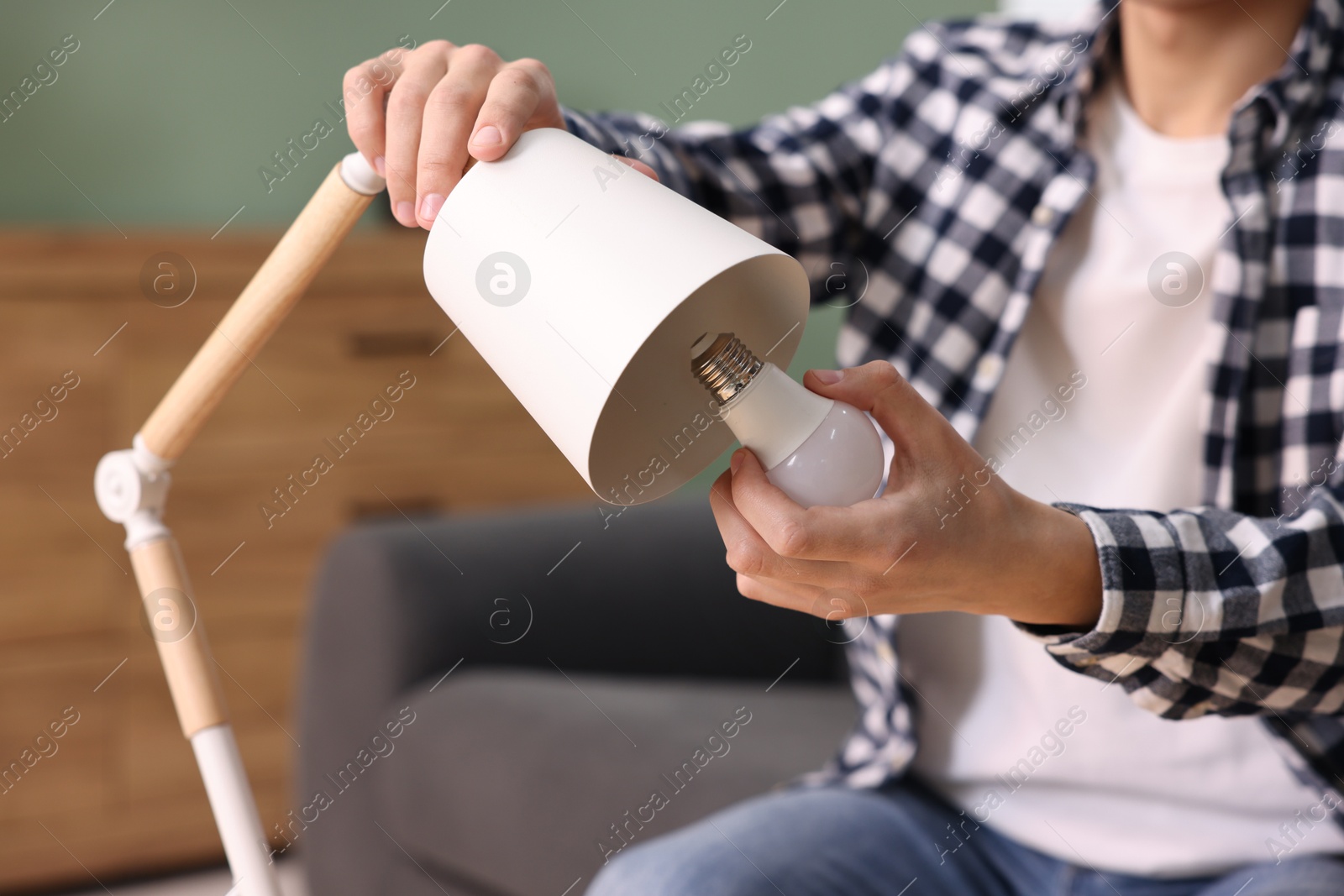 Photo of Man changing light bulb in lamp at home, closeup