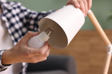 Photo of Man changing light bulb in lamp at home, closeup