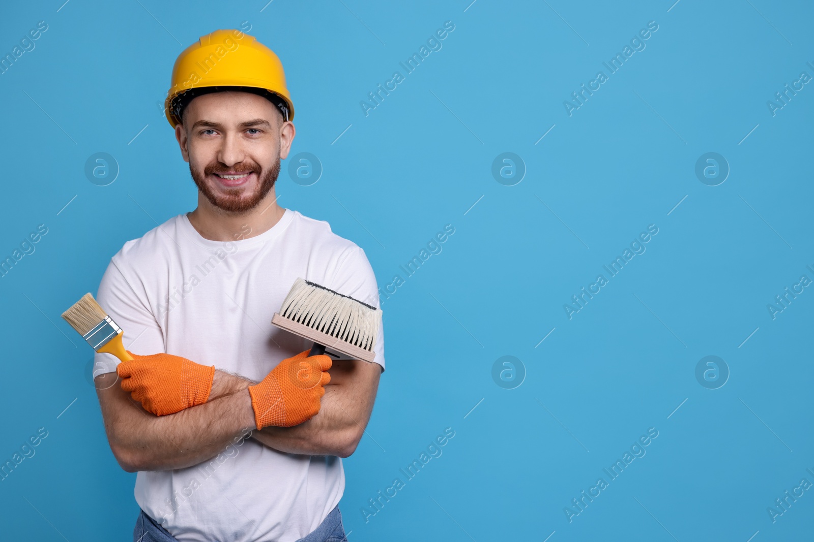 Photo of Man wearing hardhat with tools on blue background. Space for text