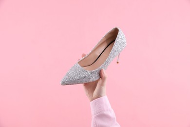 Photo of Woman with high heeled shoe on pink background, closeup