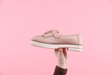 Woman with stylish shoe on pink background, closeup