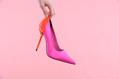 Photo of Woman with high heeled shoe on pink background, closeup