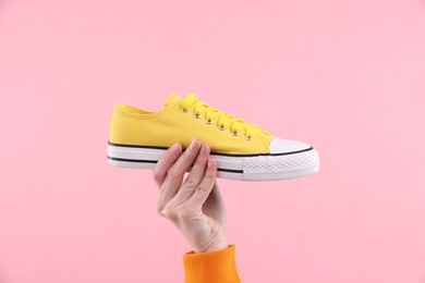 Woman with stylish sneaker on pink background, closeup