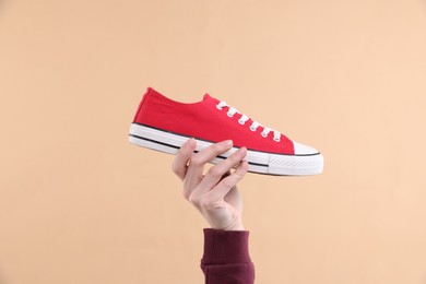 Photo of Woman with stylish sneaker on beige background, closeup