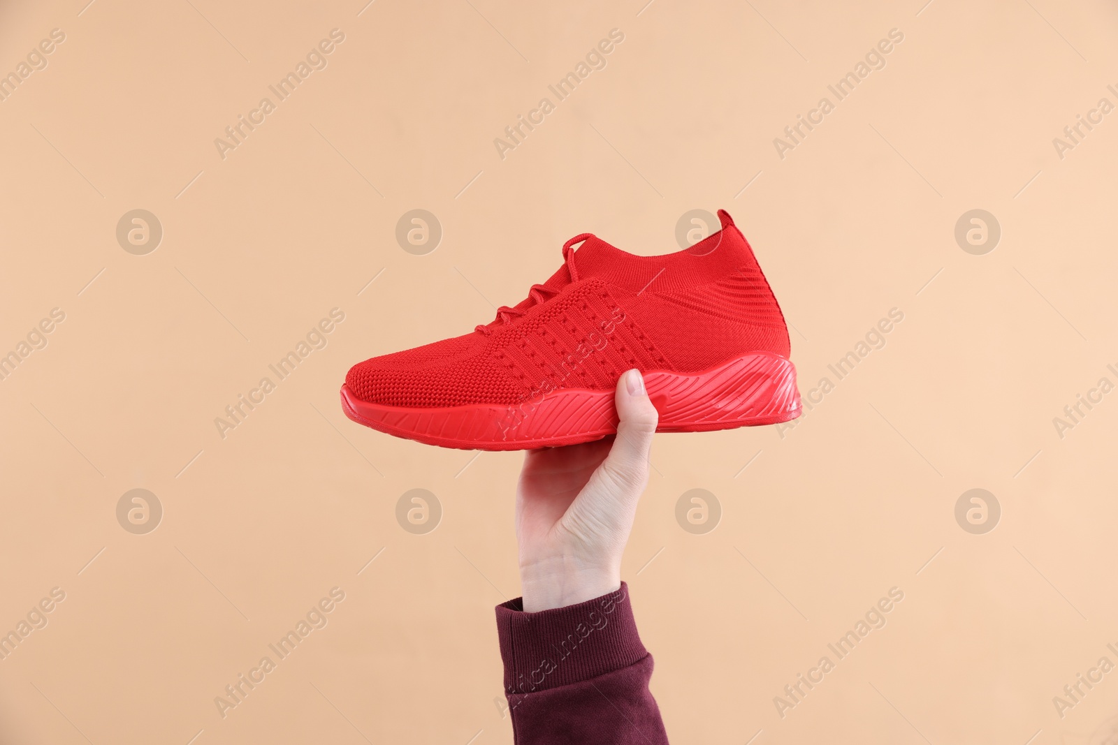 Woman with stylish sneaker on beige background, closeup Photo of Woman with stylish sneaker on beige background, closeup