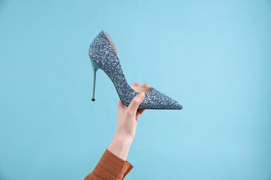 Woman with high heeled shoe on light blue background, closeup