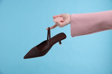 Woman with stylish shoe on light blue background, closeup