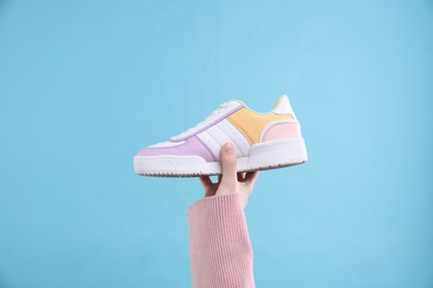 Photo of Woman with stylish sneaker on light blue background, closeup