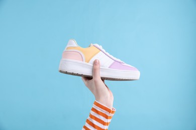 Photo of Woman with stylish sneaker on light blue background, closeup