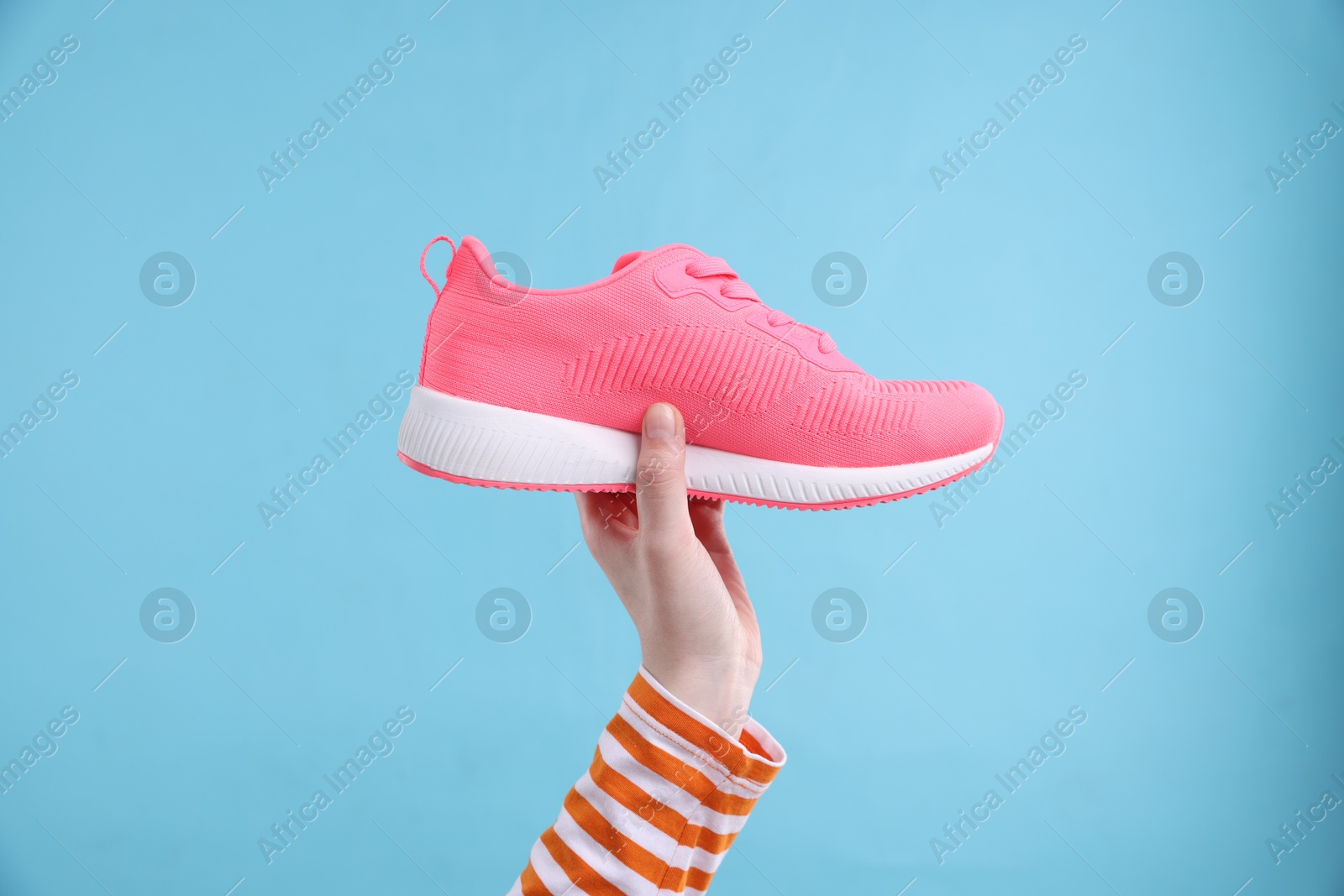 Photo of Woman with stylish sneaker on light blue background, closeup