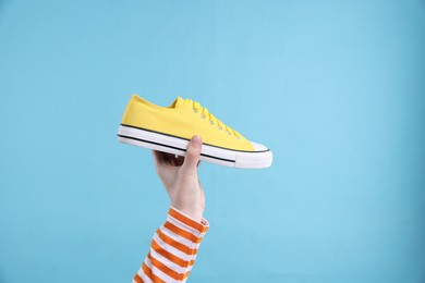 Photo of Woman with stylish sneaker on light blue background, closeup