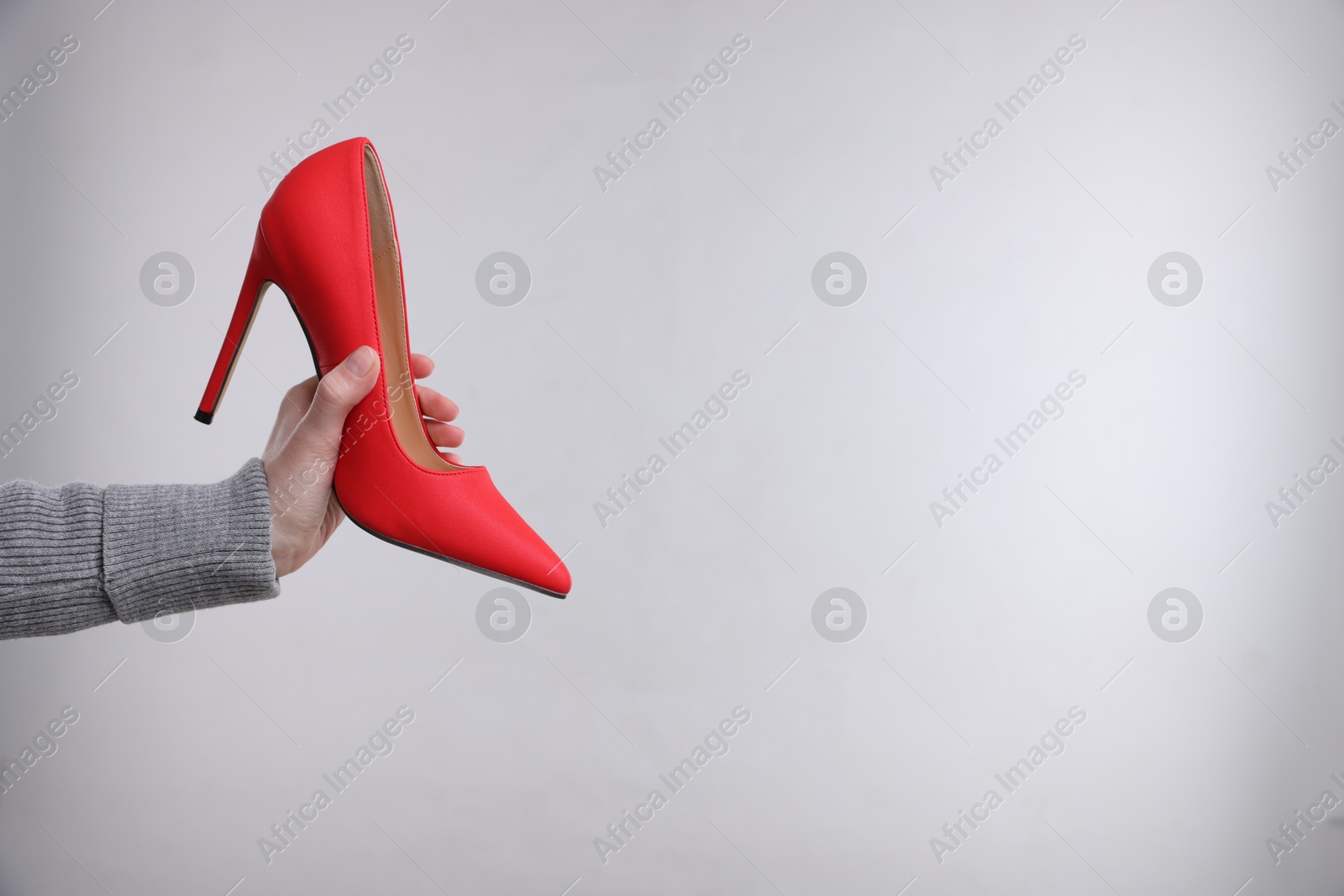 Woman with stylish high heeled shoe on grey background, closeup. Space for text Photo of Woman with stylish high heeled shoe on grey background, closeup. Space for text