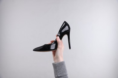 Photo of Woman with stylish high heeled shoe on grey background, closeup