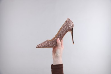 Photo of Woman with stylish high heeled shoe on grey background, closeup