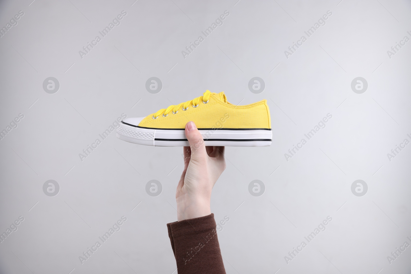 Woman with stylish sneaker on grey background, closeup Photo of Woman with stylish sneaker on grey background, closeup