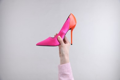 Photo of Woman with stylish high heeled shoe on grey background, closeup