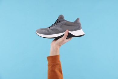 Photo of Man with stylish sneaker on light blue background, closeup