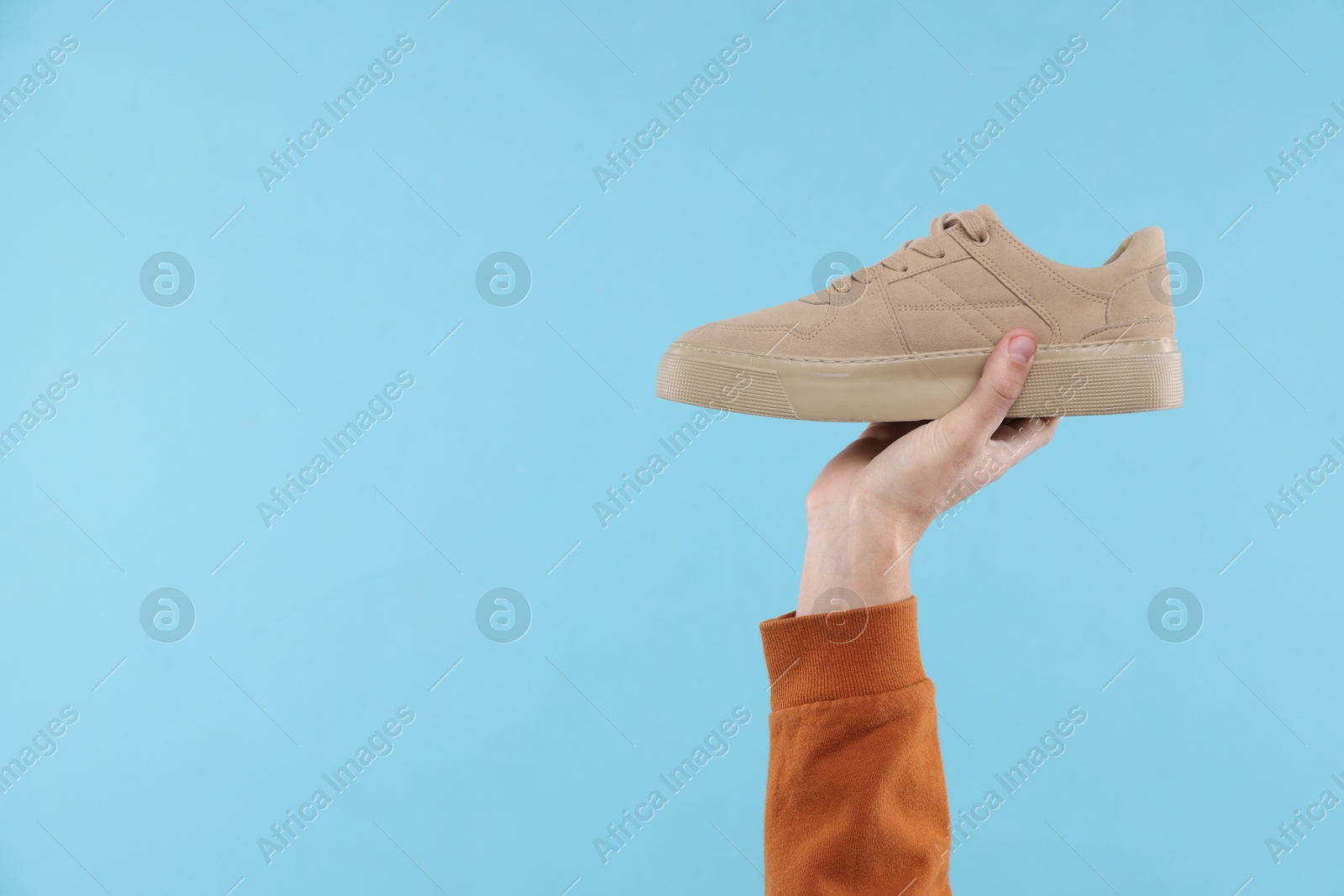 Photo of Man with stylish sneaker on light blue background, closeup. Space for text