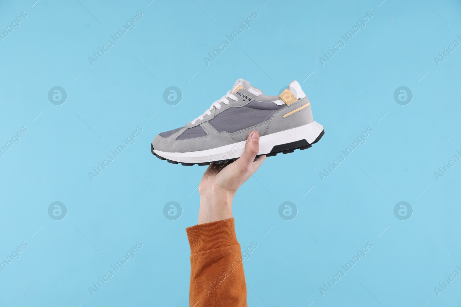 Photo of Man with stylish sneaker on light blue background, closeup