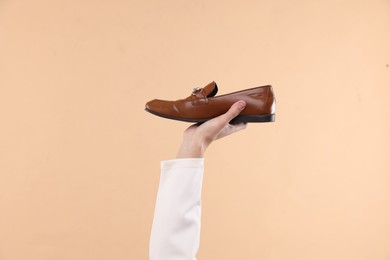 Man with stylish shoe on beige background, closeup