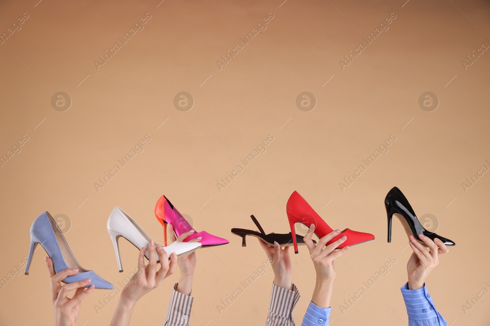 Photo of Women with different high heeled shoes on beige background, closeup. Space for text