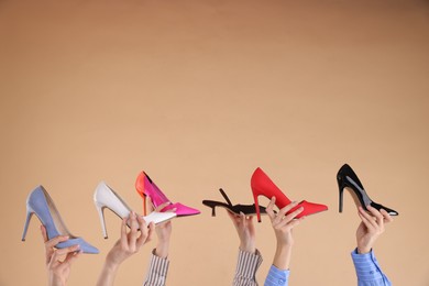 Photo of Women with different high heeled shoes on beige background, closeup. Space for text