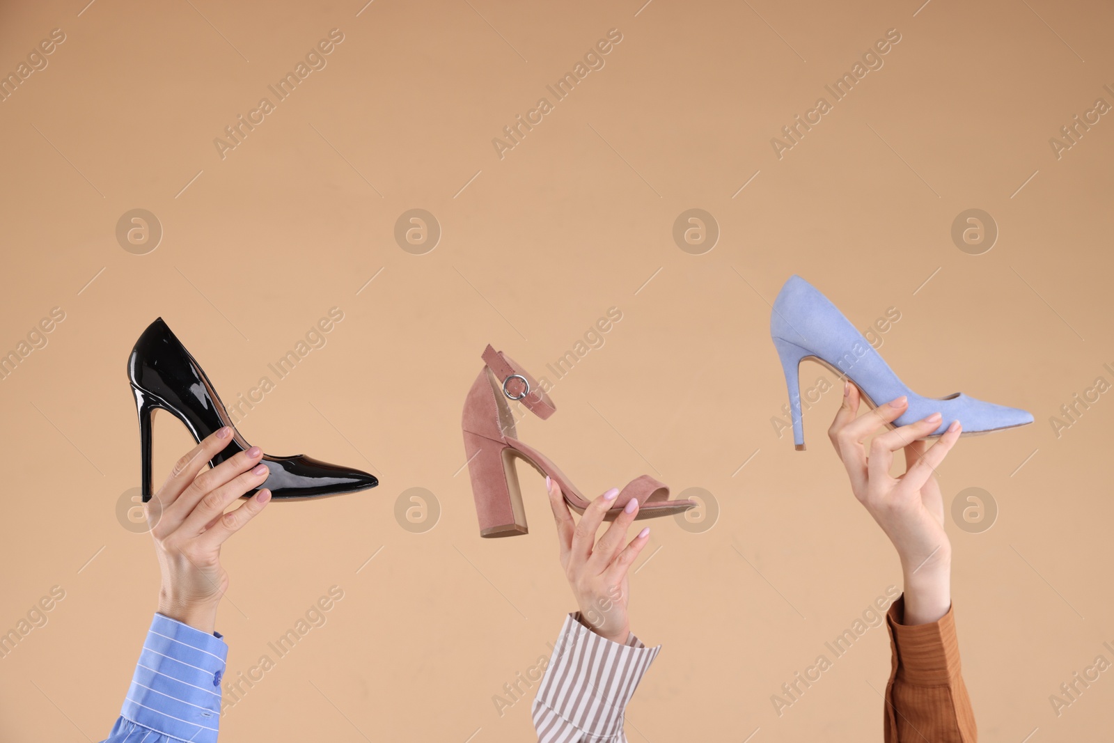 Photo of Women with different high heeled shoes on beige background, closeup