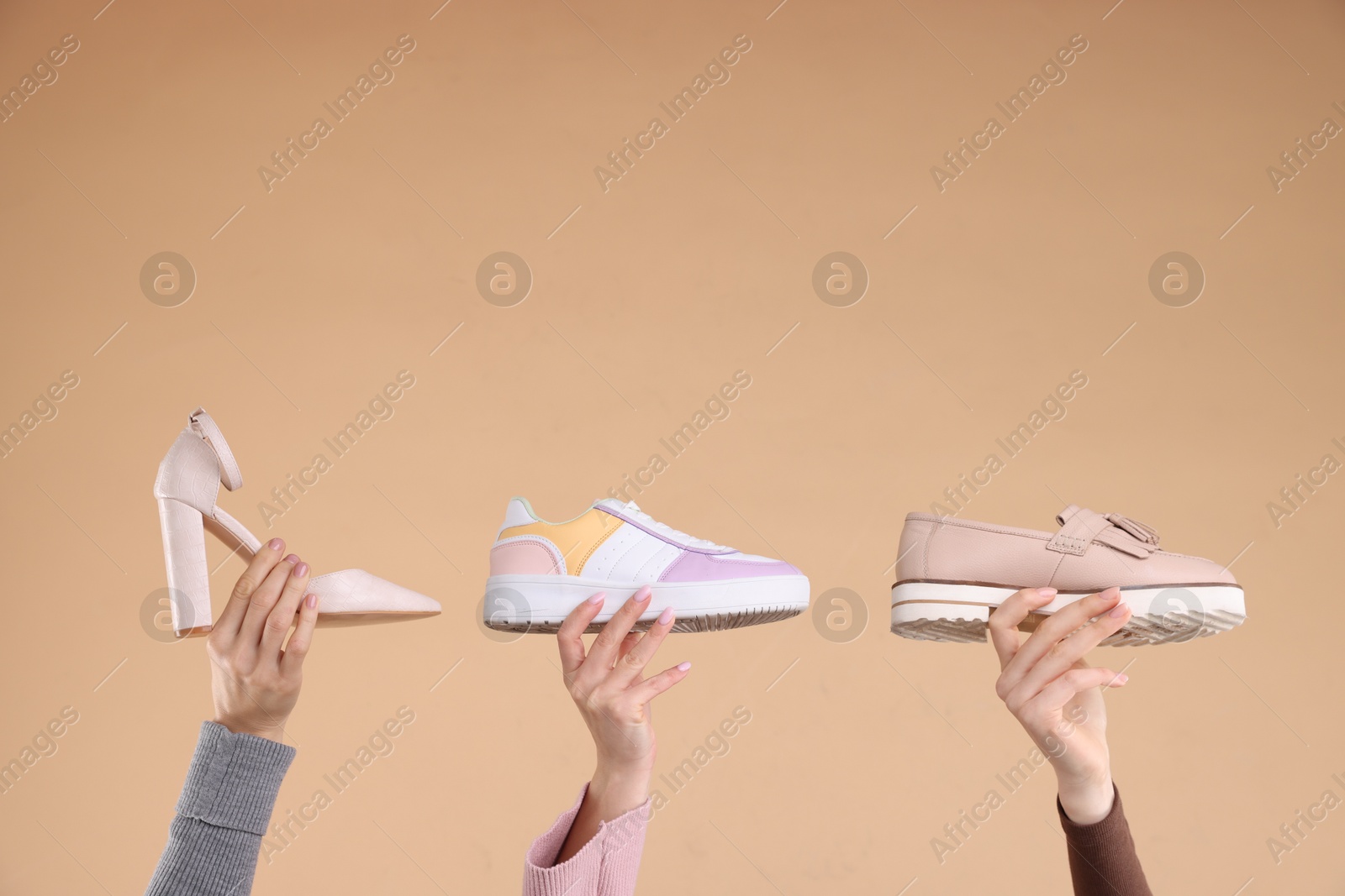 Photo of Women with different stylish shoes on beige background, closeup. Space for text