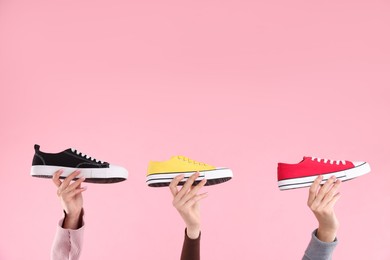 Women with different stylish sneakers on pink background, closeup. Space for text