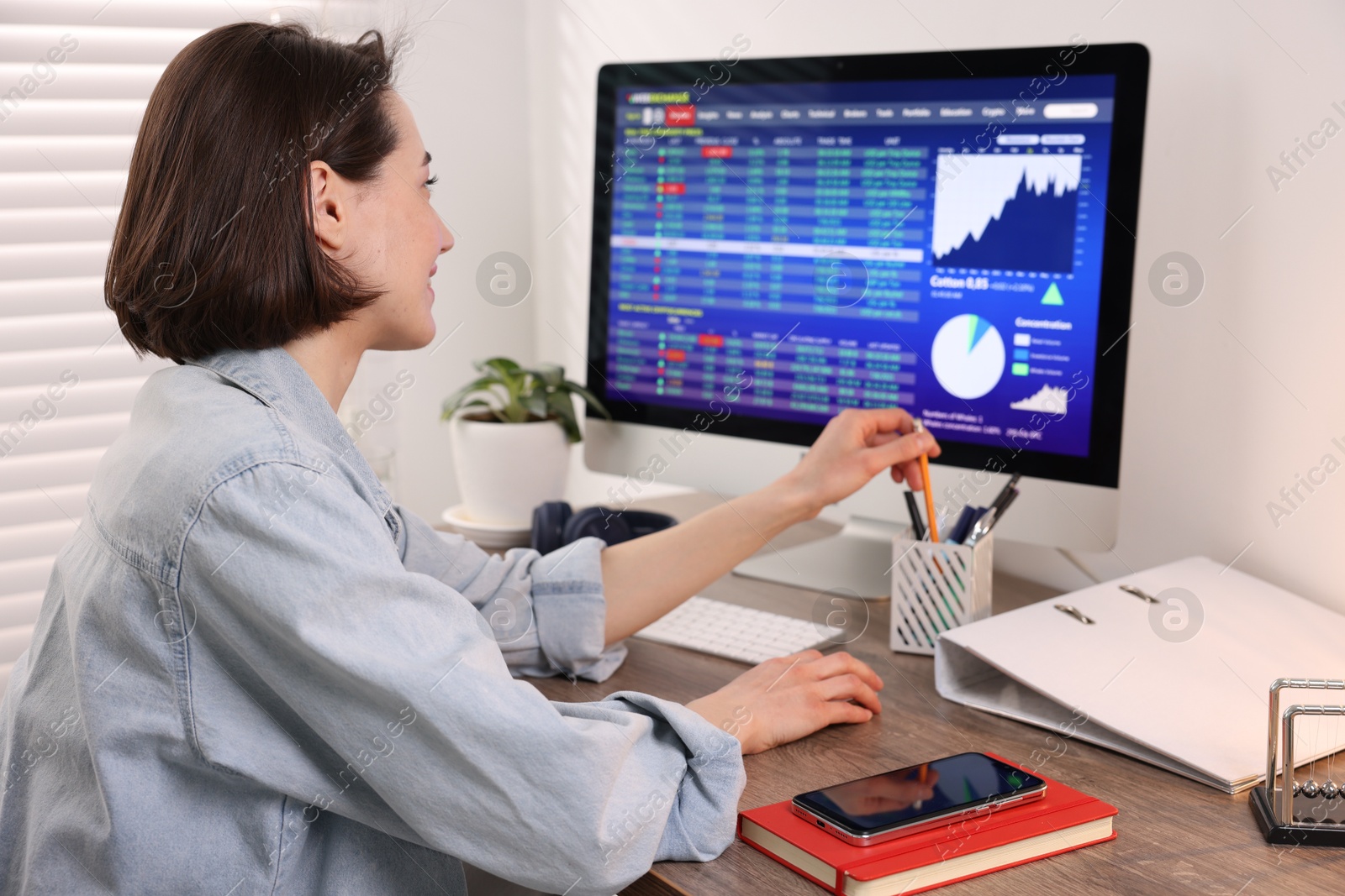 Photo of Stock exchange. Woman analysing financial market on computer at wooden table indoors