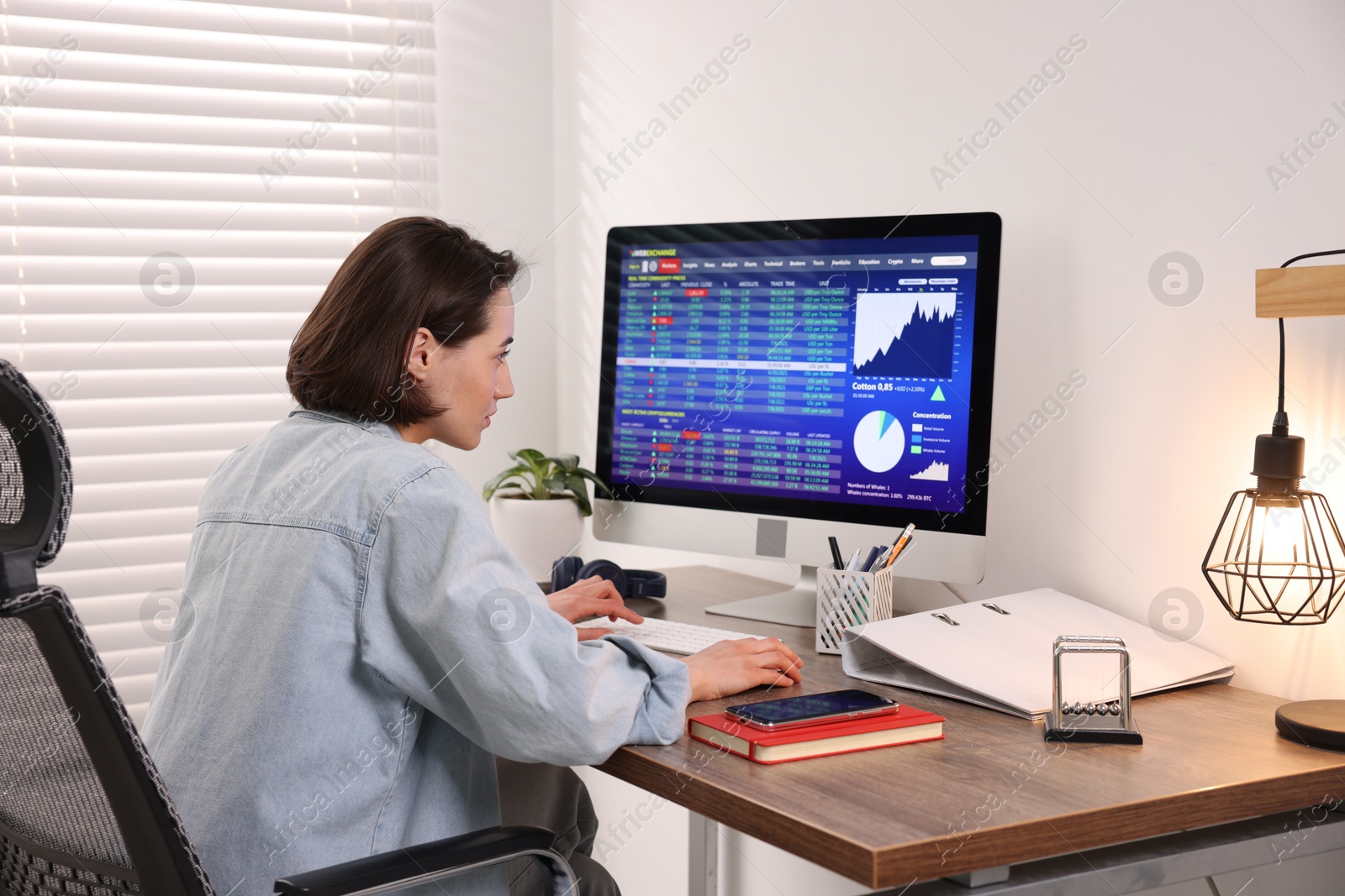 Photo of Stock exchange. Woman analysing financial market on computer at wooden table indoors