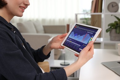 Photo of Stock exchange. Woman analysing financial market on tablet at white table indoors, closeup