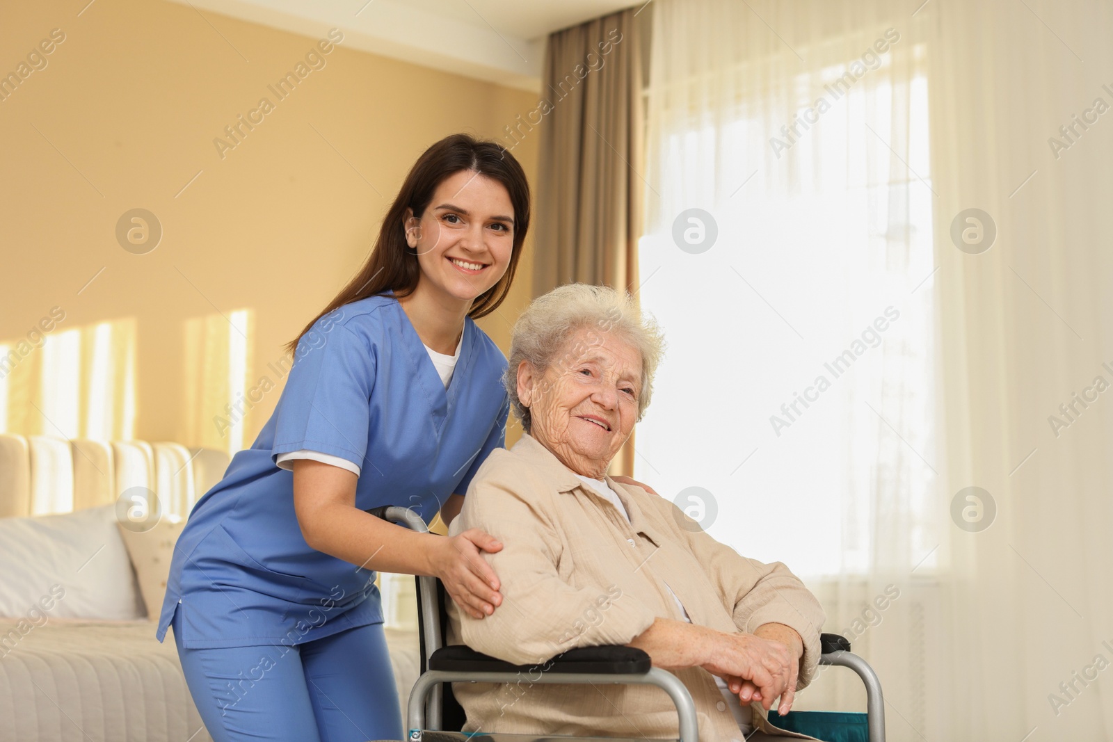 Photo of Healthcare worker with elderly woman in wheelchair indoors