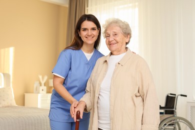 Photo of Smiling healthcare worker and elderly woman indoors