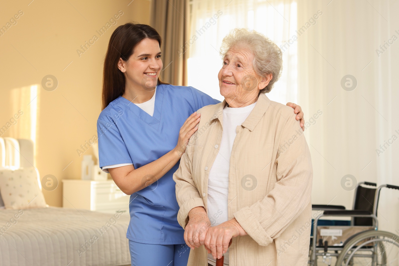 Photo of Smiling healthcare worker and elderly woman indoors