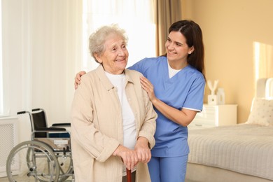 Photo of Smiling healthcare worker and elderly woman indoors