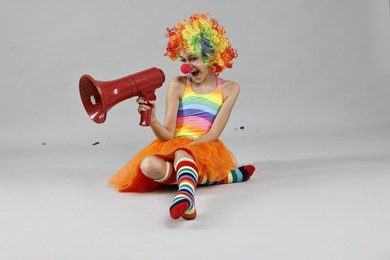 Photo of Girl dressed like clown shouting in megaphone on grey background. Surprise party