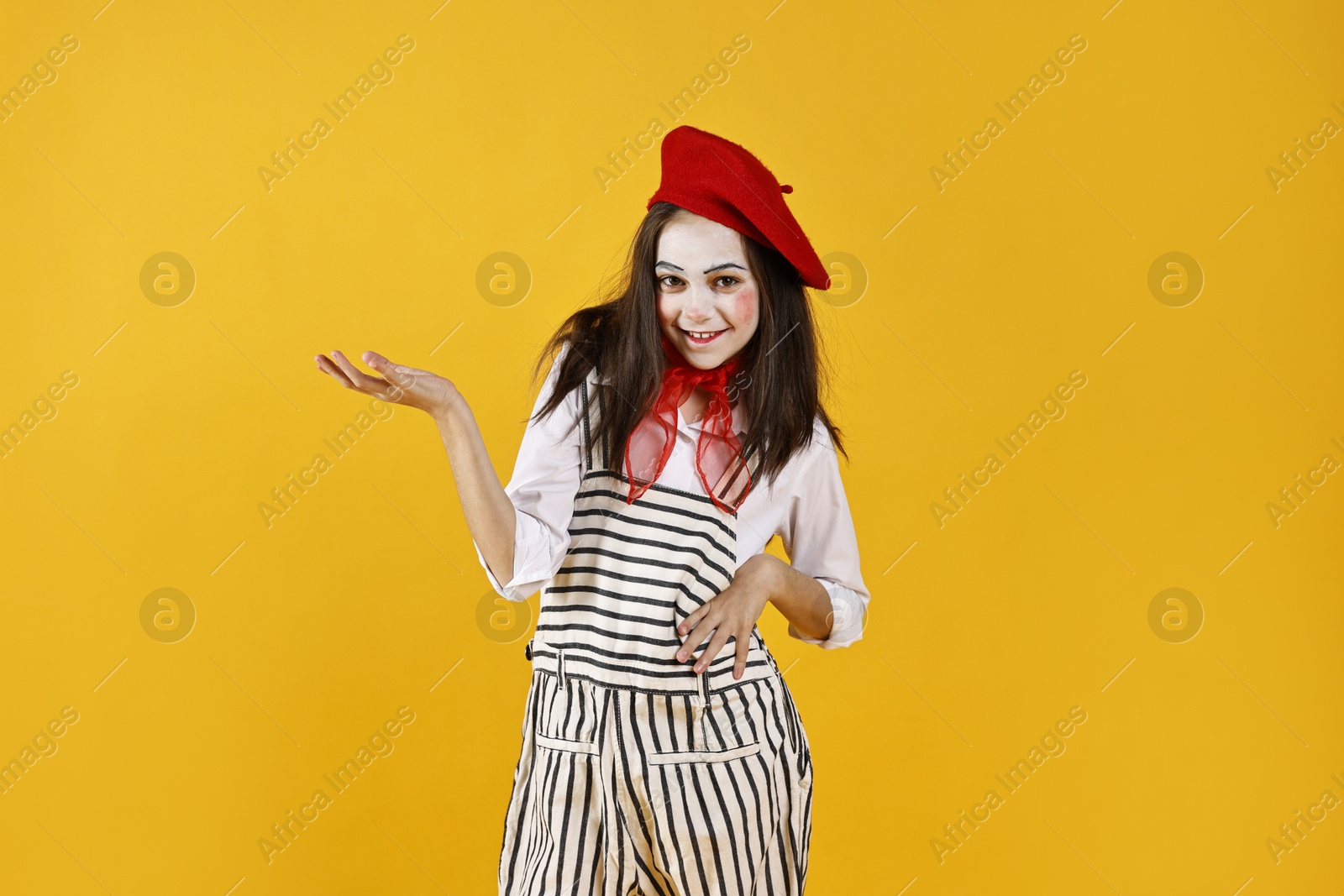 Photo of Happy girl dressed like mime holding something on yellow background. Surprise party